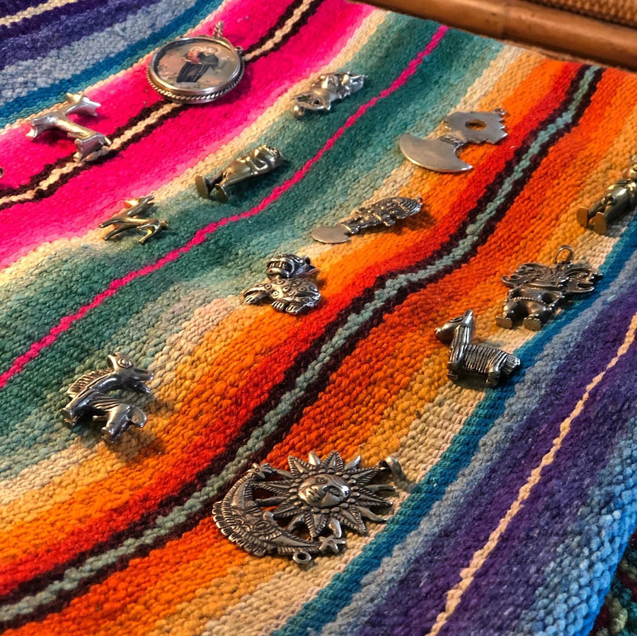 Artisanal silver pendants with Andean designs displayed on colorful Peruvian handwoven  colorful textile