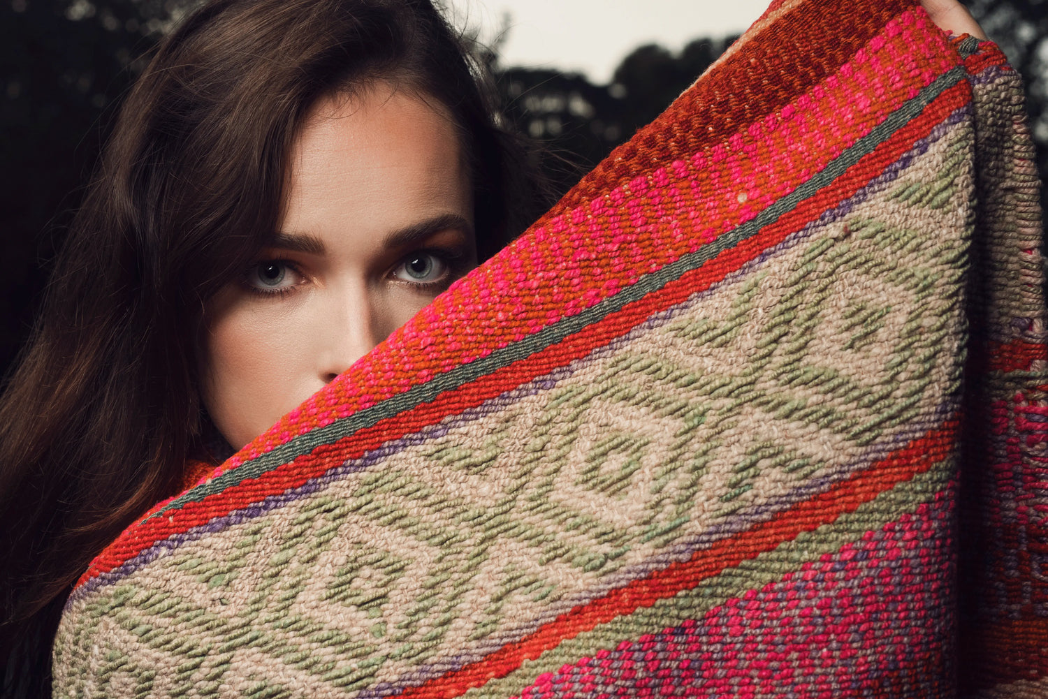 Peruvian handwoven wool rug with colorful ethnic patterns held by a woman
