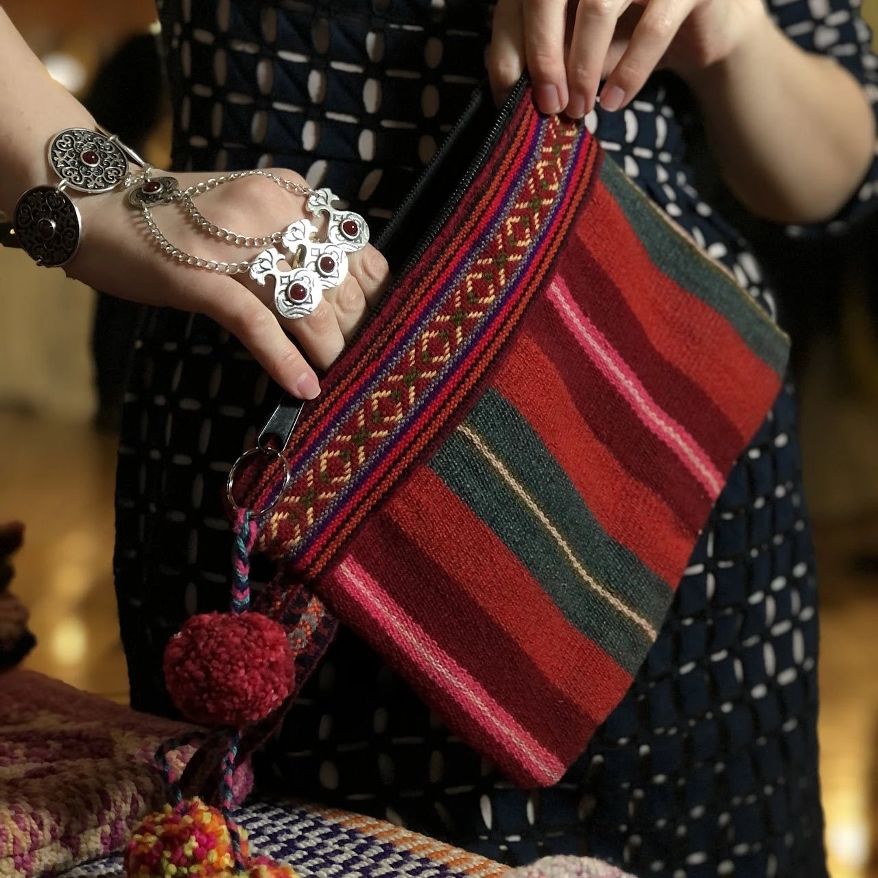 Peruvian handmade red handbag with green decorative stripes opened by a woman