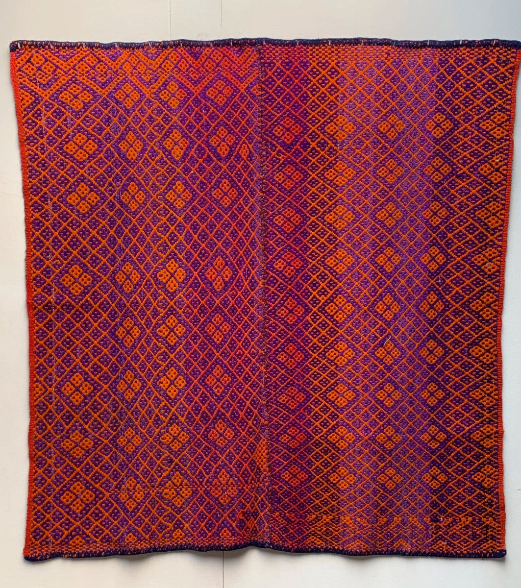 Full view of a Peruvian vintage handwoven wool rug featuring orange and purple colours with Andean diamond patterns made with natural dyes.