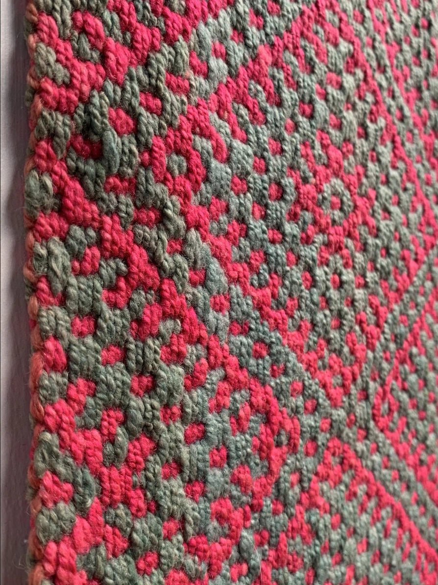Peruvian vintage handwoven wool rug, detailed close-up  from the side of tightly woven Andean diamond patterns in pink and green.
