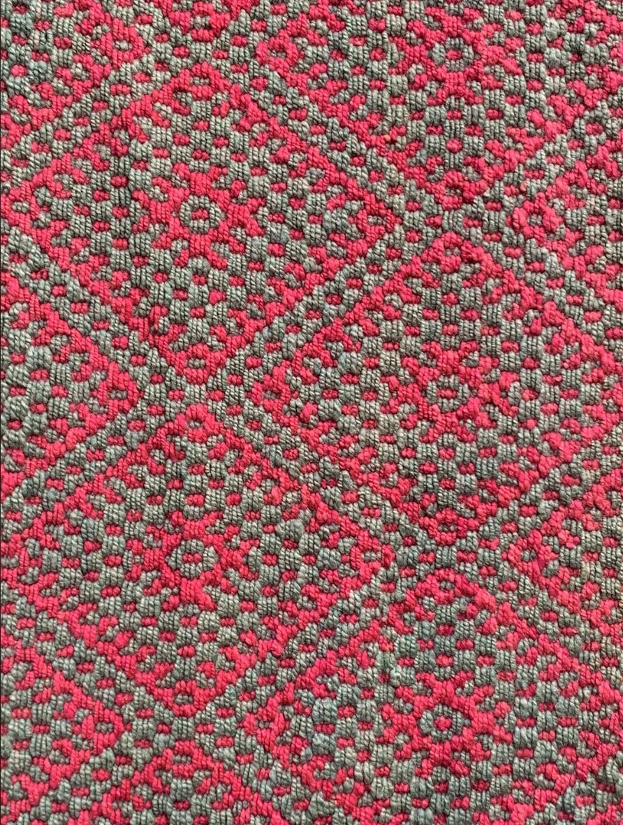 Peruvian handwoven wool rug, medium close-up of pink and green with Andean diamond motifs showing detailed weaving.