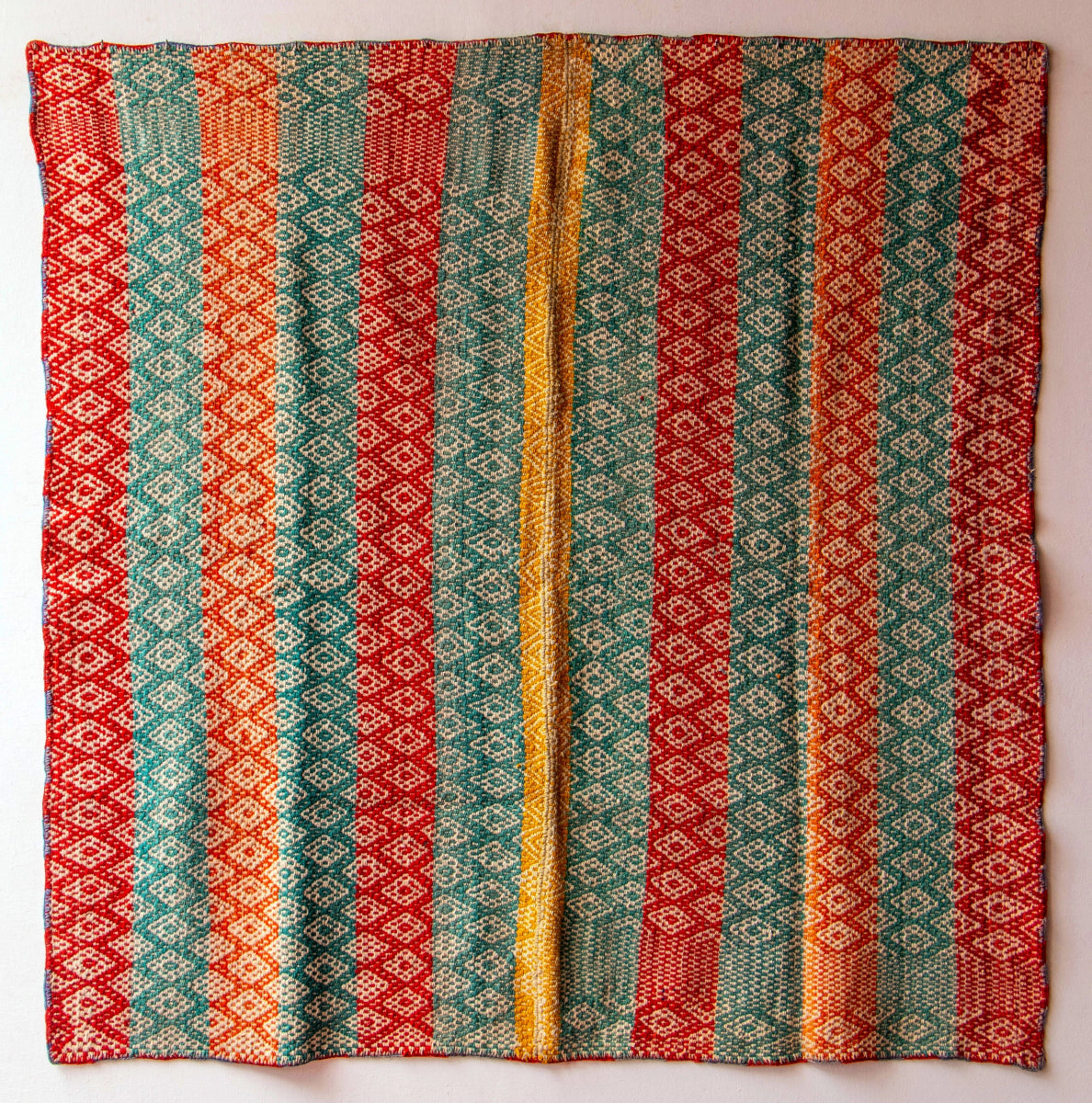 Full view of a Peruvian vintage handwoven wool rug featuring red, turquoise and yellow with Andean diamond patterns made with natural dyes.