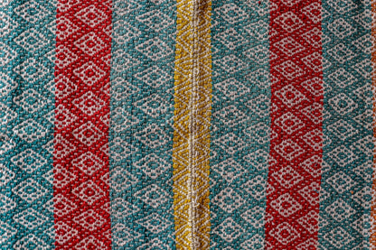 Peruvian handwoven wool rug, medium close-up of red, turquoise and yellow with Andean diamond motifs showing detailed weaving.