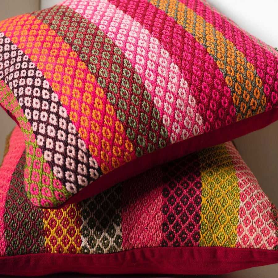 Two colorful Peruvian pillow covers with geometric designs, handwoven and stacked on neutral background
